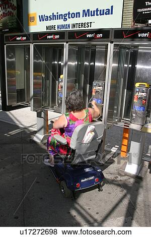 Stock Photo - A woman trying to use non accessible pay phones.. Fotosearch