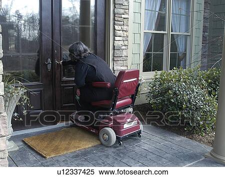 A woman using a wheelchair enters her home. View Large Photo Image Stock Photography - A woman using a wheelchair enters her home.. Fotosearch