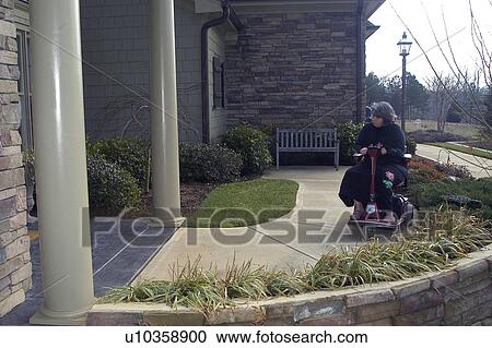 A woman using a wheelchair wheels toward the front door of a friend’s house. View Large Photo Image Stock Image - A woman using a wheelchair wheels toward the front door of a friend’s house.. Fotosearch