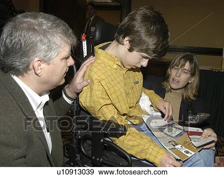 Boy with disabilities looking at assistive technology magazines while his parents discuss the pictures View Large Photo Image Stock Photo - Boy with disabilities looking at assistive technology magazines while his parents discuss the pictures. Fotosearch