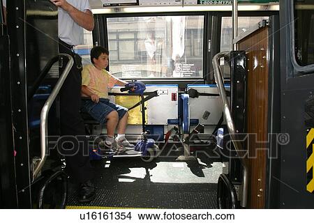 Picture - Boy with Muscular Dystrophy, utilizing a scooter/cart for mobility, using a city bus.. Fotosearch