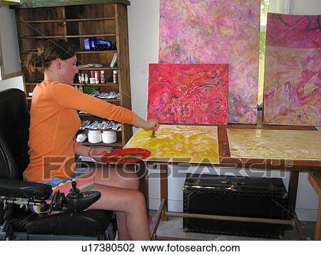 Stock Image - Female artist (wheelchair user) works with oils in her studio.. Fotosearch