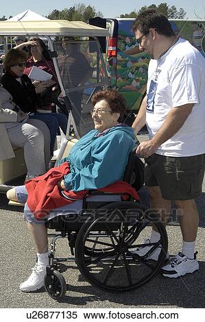 Man guides woman in wheelchair (single amputee) through community fair View Large Photo Image Stock Photography - Man guides woman in wheelchair (single amputee) through community fair. Fotosearch