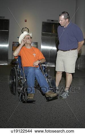 Man with a disability, utilizing a wheelchair for mobility, enjoying an afternoon with his friend. View Large Photo Image Picture - Man with a disability, utilizing a wheelchair for mobility, enjoying an afternoon with his friend.. Fotosearch