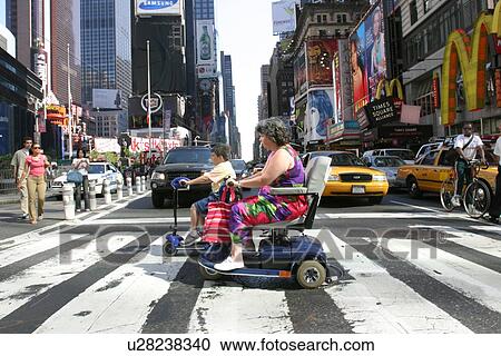 Stock Image - Mother and son crossing a city street using scooters/carts.. Fotosearch