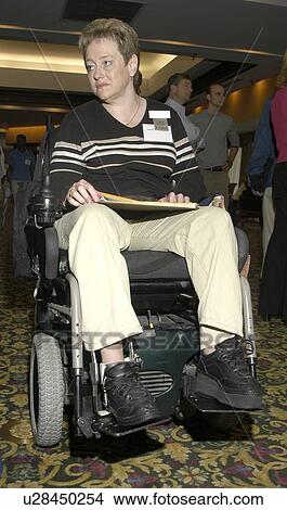 Picture - Professional woman sitting in electric wheelchair holding a notepad of paper.. Fotosearch