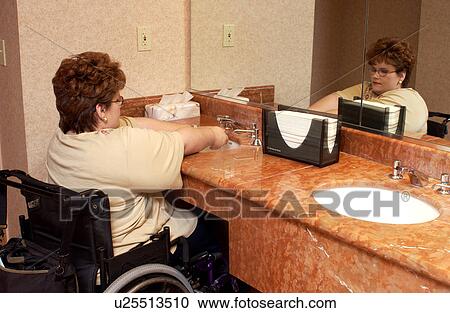 Woman with a disability, utilizing a wheelchair for mobility, washing her hands after using the restroom. View Large Photo Image Stock Image - Woman with a disability, utilizing a wheelchair for mobility, washing her hands after using the restroom.. Fotosearch