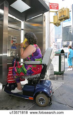 Woman with a disability, utilizing a scooter for mobility, using a public pay telephone View Large Photo Image Stock Photo - Woman with a disability, utilizing a scooter for mobility, using a public pay telephone. Fotosearch