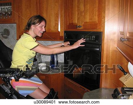 Young woman (electric wheelchair user) laughs as she sets the baking time on her oven in an accessible kitchen. View Large Photo Image Stock Image - Young woman (electric wheelchair user) laughs as she sets the baking time on her oven in an accessible kitchen.. Fotosearch