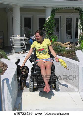 Young woman (electric wheelchair user) pets her dog as she enters the ramp to her accessible pool View Large Photo Image Stock Photograph - Young woman (electric wheelchair user) pets her dog as she enters the ramp to her accessible pool. Fotosearch
