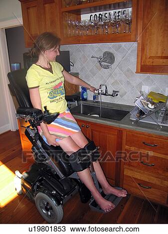 Young woman elevates her power wheelchair to wash dishes in her accessible kitchen. View Large Photo Image Stock Image - Young woman elevates her power wheelchair to wash dishes in her accessible kitchen.. Fotosearch