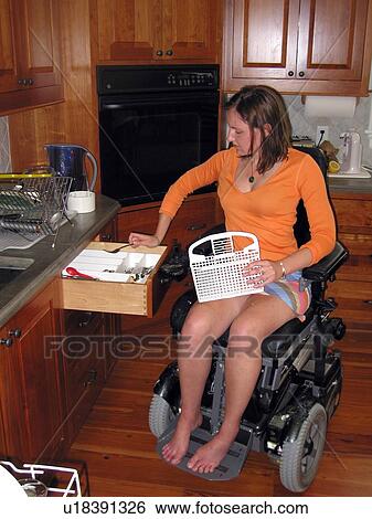Young woman (wheelchair user) puts clean silverware back in the drawer in an accessible kitchen. View Large Photo Image Stock Photograph - Young woman (wheelchair user) puts clean silverware back in the drawer in an accessible kitchen.. Fotosearch