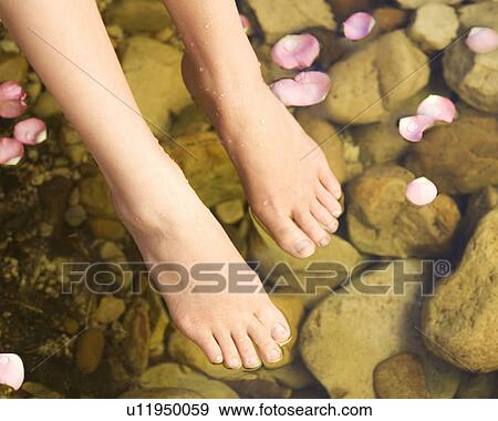 Stock Photo - Close-up of feet in a natural pool. Fotosearch