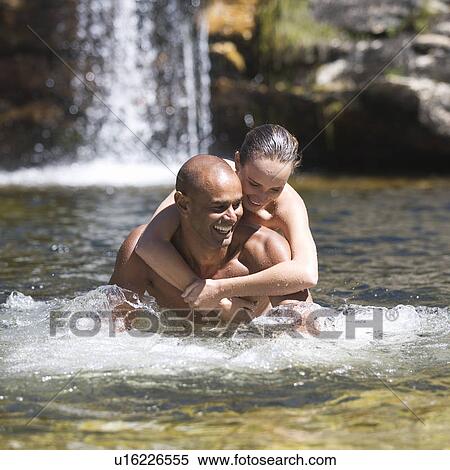 Stock Photography - Young couple embracing in a natural pool. Fotosearch