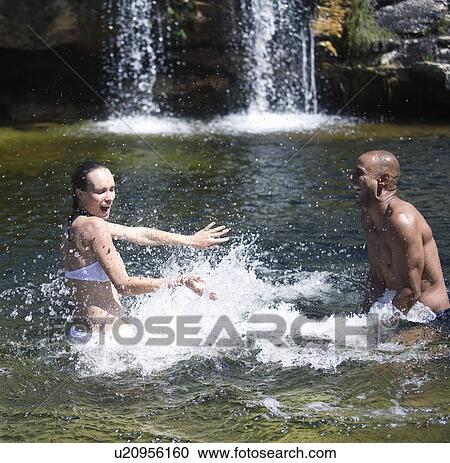 Young couple playing in a natural pool View Large Photo Image Stock Image - Young couple playing in a natural pool. Fotosearch