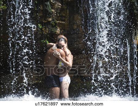 Stock Photo - Young couple standing in a waterfall, embracing. Fotosearch