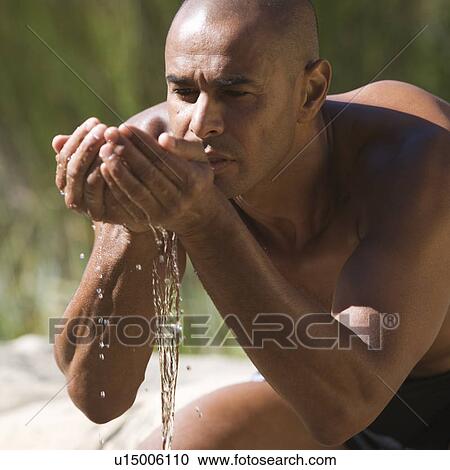 Young man drinking water from cupped hands, close-up View Large Photo Image Stock Image - Young man drinking water from cupped hands, close-up. Fotosearch