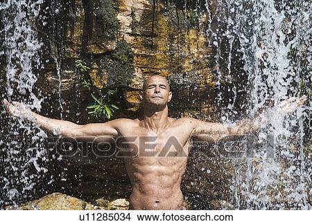 Young man standing in a waterfall View Large Photo Image Picture - Young man standing in a waterfall. Fotosearch