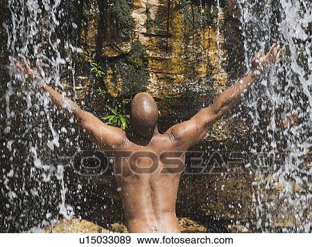 Young man standing in a waterfall View Large Photo Image Stock Photo - Young man standing in a waterfall. Fotosearch