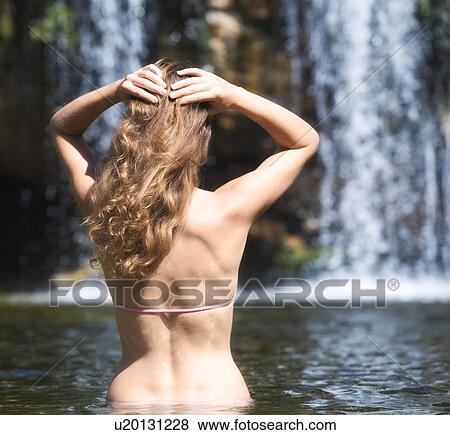 Stock Photo - Young woman in a bikini standing in a natural pool. Fotosearch