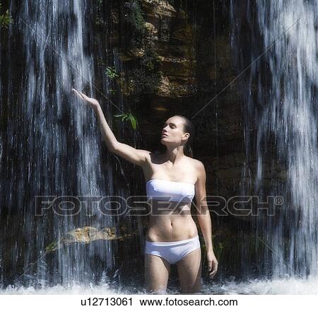 Young woman standing in a waterfall View Large Photo Image Stock Image - Young woman standing in a waterfall. Fotosearch