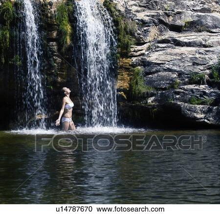 Young woman standing in a waterfall View Large Photo Image Stock Image - Young woman standing in a waterfall. Fotosearch