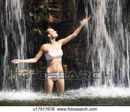 Young woman standing in a waterfall View Large Photo Image Stock Photo - Young woman standing in a waterfall. Fotosearch