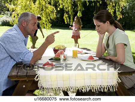 Stock Photography - A couple arguing whilst in the garden with their children. Fotosearch