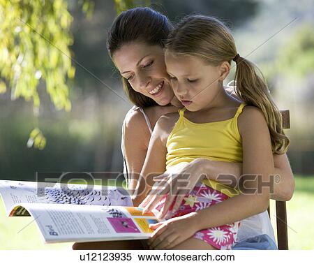 A woman and young girl sitting in the garden reading a book View Large Photo Image Stock Photography - A woman and young girl sitting in the garden reading a book. Fotosearch