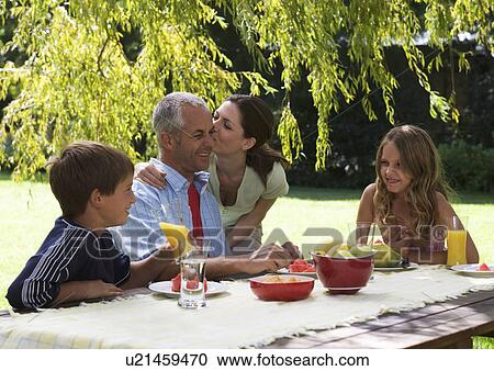 Stock Image - Family having lunch in the garden. Fotosearch