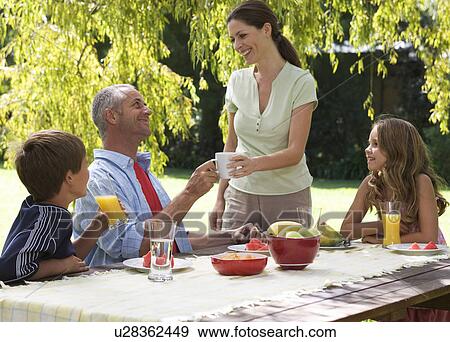 Stock Photo - Family having lunch in the garden. Fotosearch