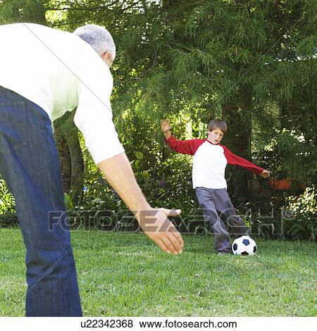 Father and son playing football in a garden View Large Photo Image Stock Photo - Father and son playing football in a garden. Fotosearch