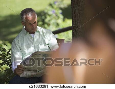Man sitting in a garden reading a newspaper View Large Photo Image Stock Image - Man sitting in a garden reading a newspaper. Fotosearch
