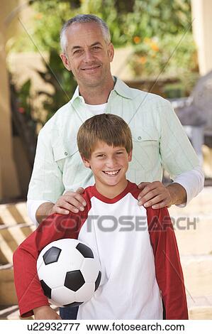 Portrait of a father with his young son, holding a football View Large Photo Image Stock Photo - Portrait of a father with his young son, holding a football. Fotosearch