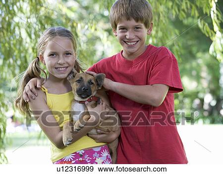 Young boy and girl holding a puppy View Large Photo Image Stock Photo - Young boy and girl holding a puppy. Fotosearch