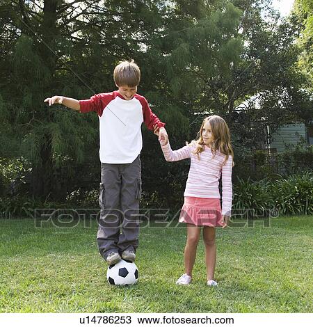 Young boy and girl playing with a football in a garden View Large Photo Image Stock Image - Young boy and girl playing with a football in a garden. Fotosearch
