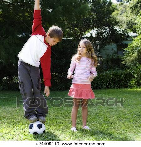 Stock Photo - Young boy and girl playing with a football in a garden. Fotosearch