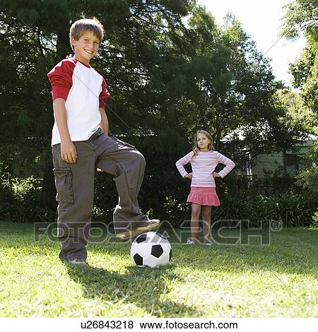 Stock Photo - Young boy and girl playing with a football in a garden. Fotosearch