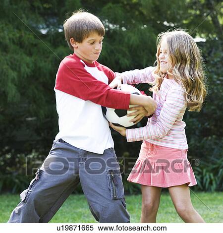 Stock Photography - Young boy and girl playing with a football in a garden. Fotosearch