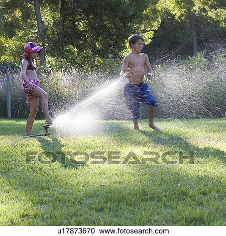 Young boy and girl playing with water in the garden View Large Photo Image Stock Image - Young boy and girl playing with water in the garden. Fotosearch