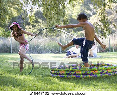 Young girl and boy playing in a paddling pool View Large Photo Image Stock Image - Young girl and boy playing in a paddling pool. Fotosearch