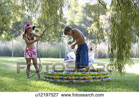 Young girl and boy playing in a paddling pool View Large Photo Image Stock Photo - Young girl and boy playing in a paddling pool. Fotosearch