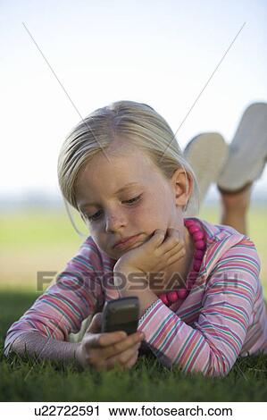 Stock Image - A young girl playing with a mobile phone. Fotosearch