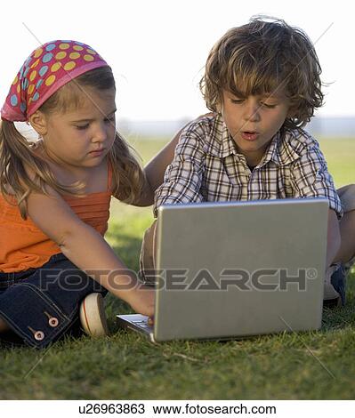 Two young children playing with a laptop computer View Large Photo Image Stock Image - Two young children playing with a laptop computer. Fotosearch