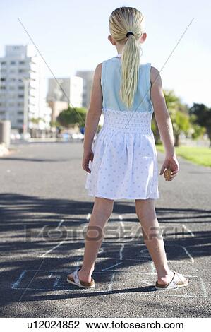 Stock Image - Young girl playing hopscotch. Fotosearch