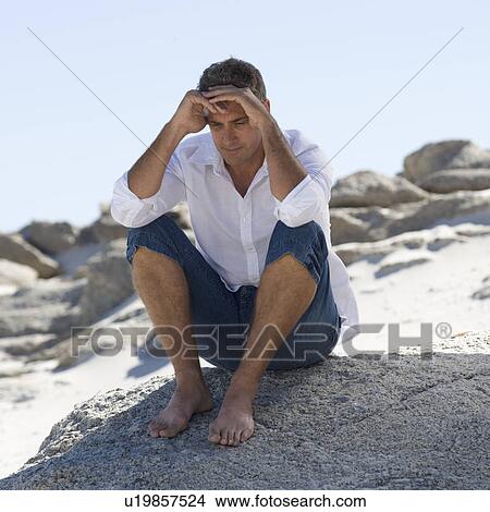 A man sitting on rocks View Large Photo Image Picture - A man sitting on rocks. Fotosearch