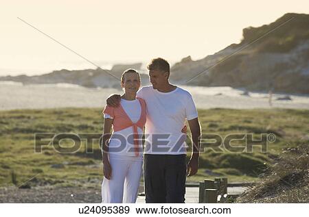 Stock Photo - A mature couple walking on the coast. Fotosearch