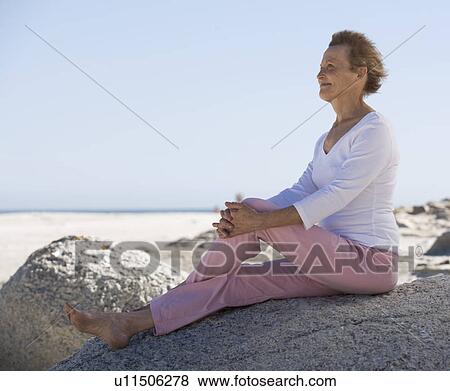A mature woman sitting on a beach View Large Photo Image Stock Photo - A mature woman sitting on a beach. Fotosearch