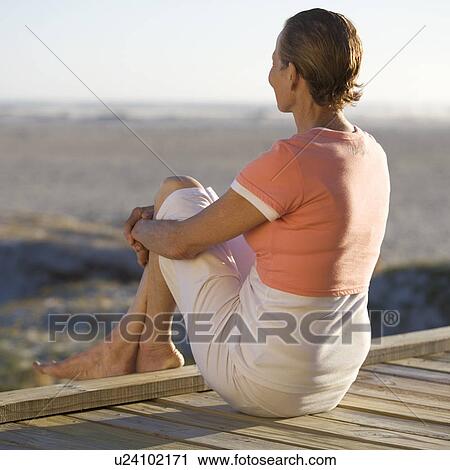 A mature woman sitting on a boardwalk View Large Photo Image Stock Image - A mature woman sitting on a boardwalk. Fotosearch