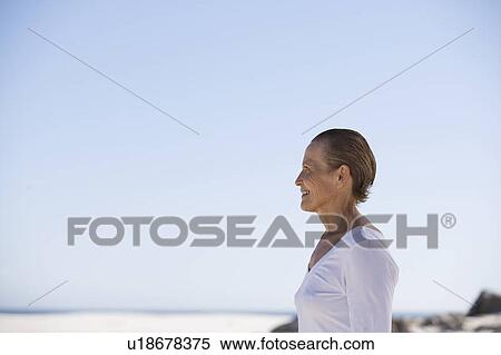 Stock Photography - A mature woman standing on a beach. Fotosearch